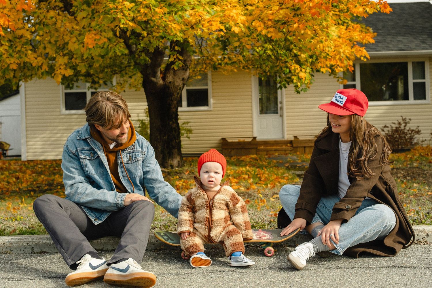 People sitting on autumn grass reading books together with golden fall foliage in the background.