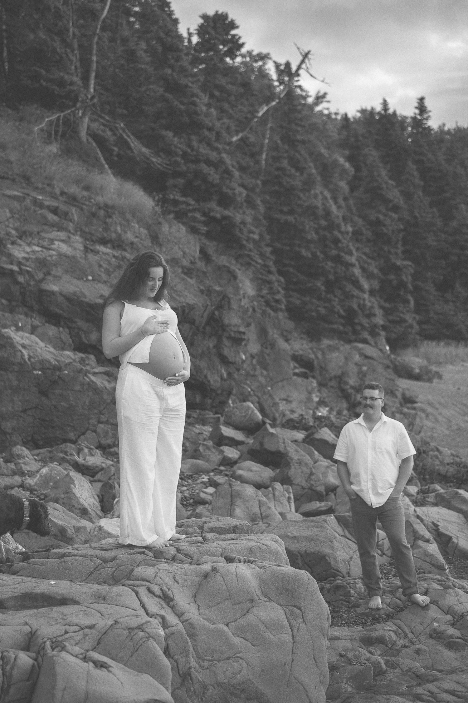 People in white clothing pose along a rocky coastal shoreline in black and white photographs.
