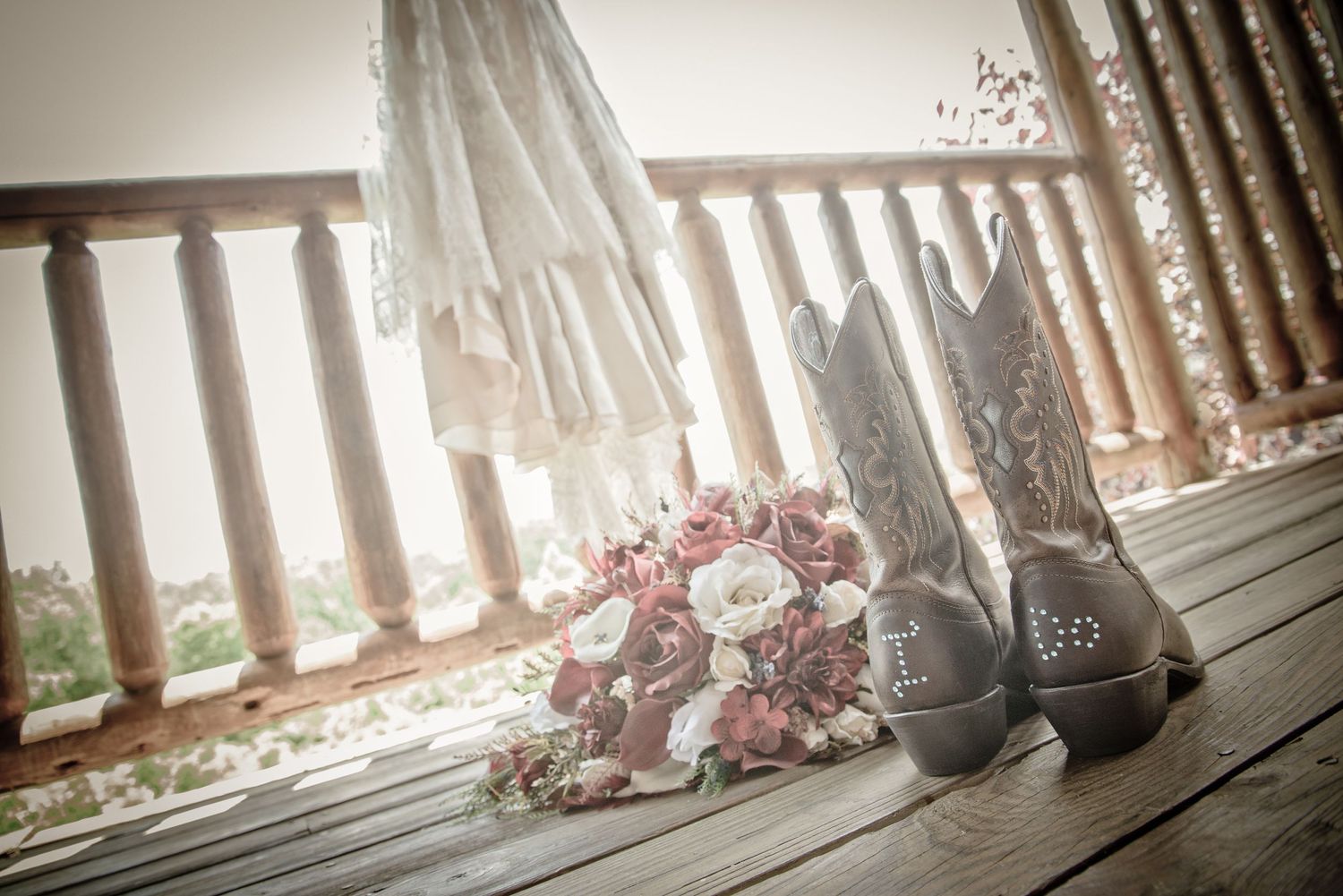 Pigeon Forge Wedding Photographers wedding shoes and bouquet arranged on rustic wooden deck with railing and sunlit bridal dress .