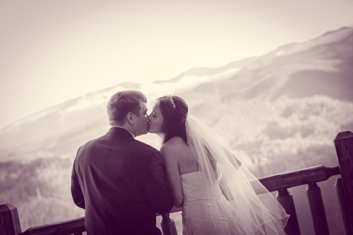 A romantic black and white wedding moment on a mountain overlook with a couple seated together.