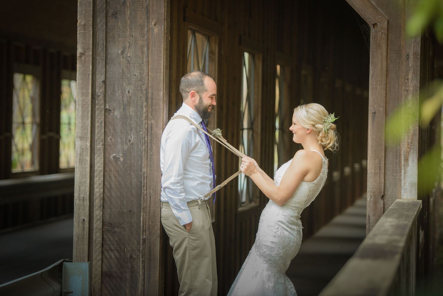 A couple shares a joyful moment together in a rustic covered wooden bridge on their wedding day by Gatlinburg Wedding Photographers.