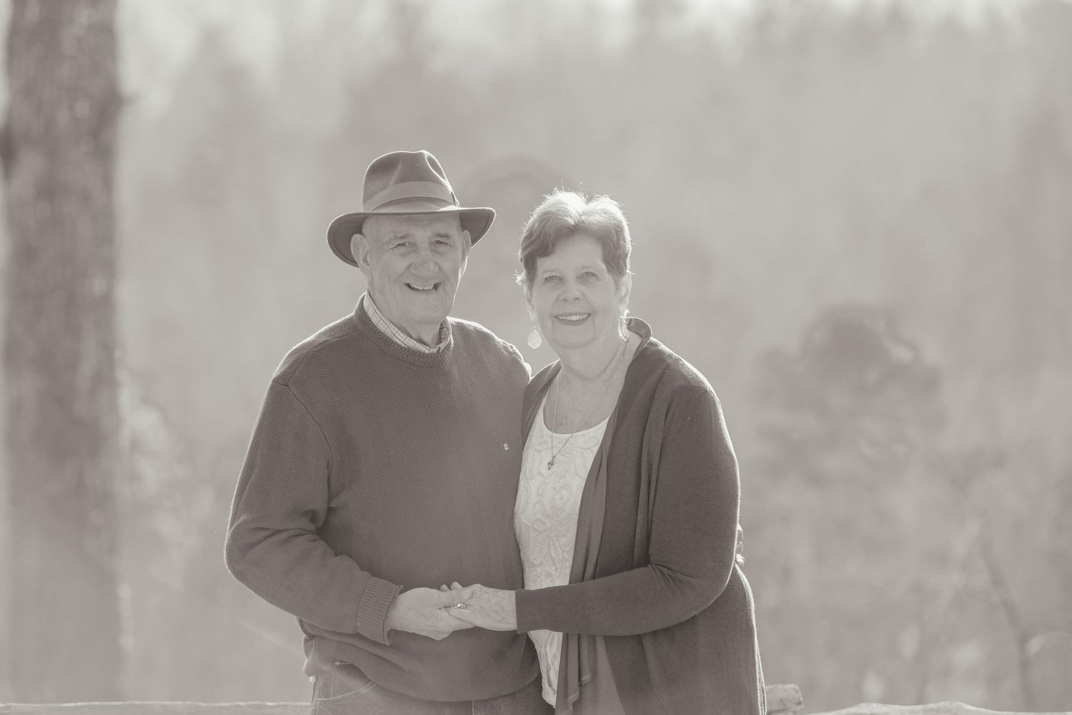 A vintage outdoor portrait of a couple standing close together on a misty day, wearing casual attire for anniversary pictures in Gatlinburg.
