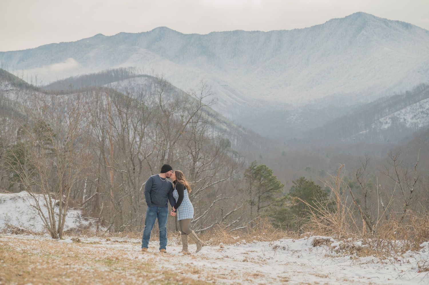 A couple shares a tender moment overlooking misty mountain vistas on a cold winter day in the wilderness by Gatlinburg TN Photographers.