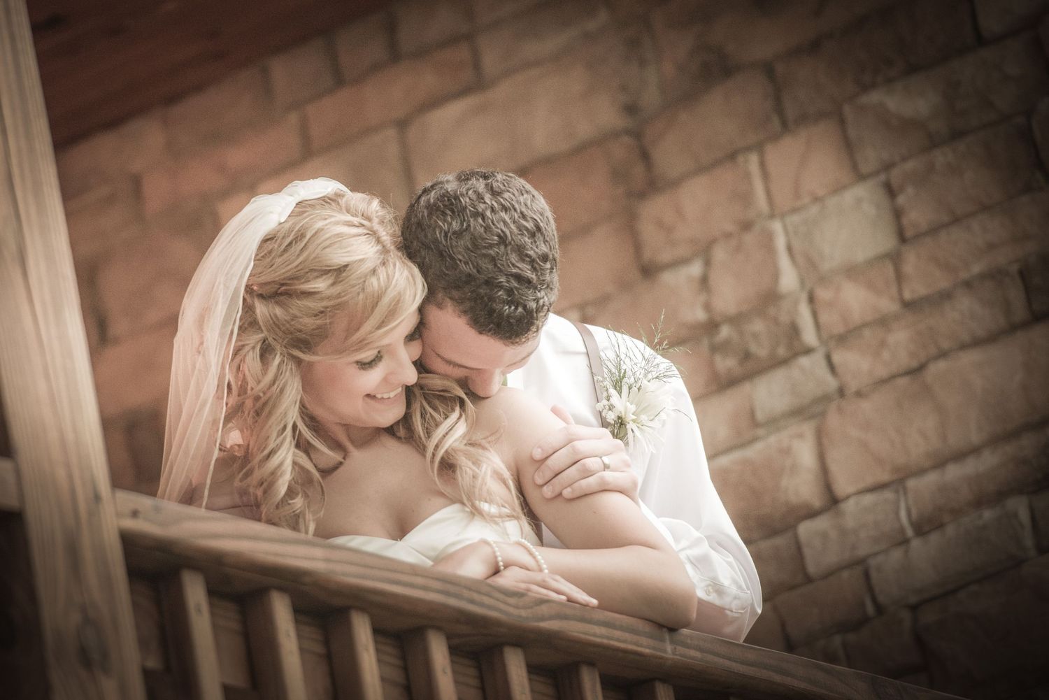 A romantic wedding moment on a rustic wooden balcony against stone walls by Gatlinburg TN Wedding Photographers.
