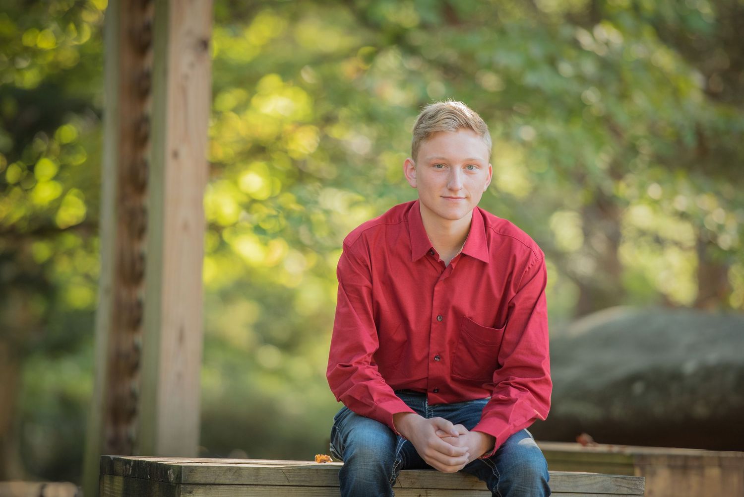 pigeon forge school pictures photographers of Senior boy in red shit with green foliage int he background.