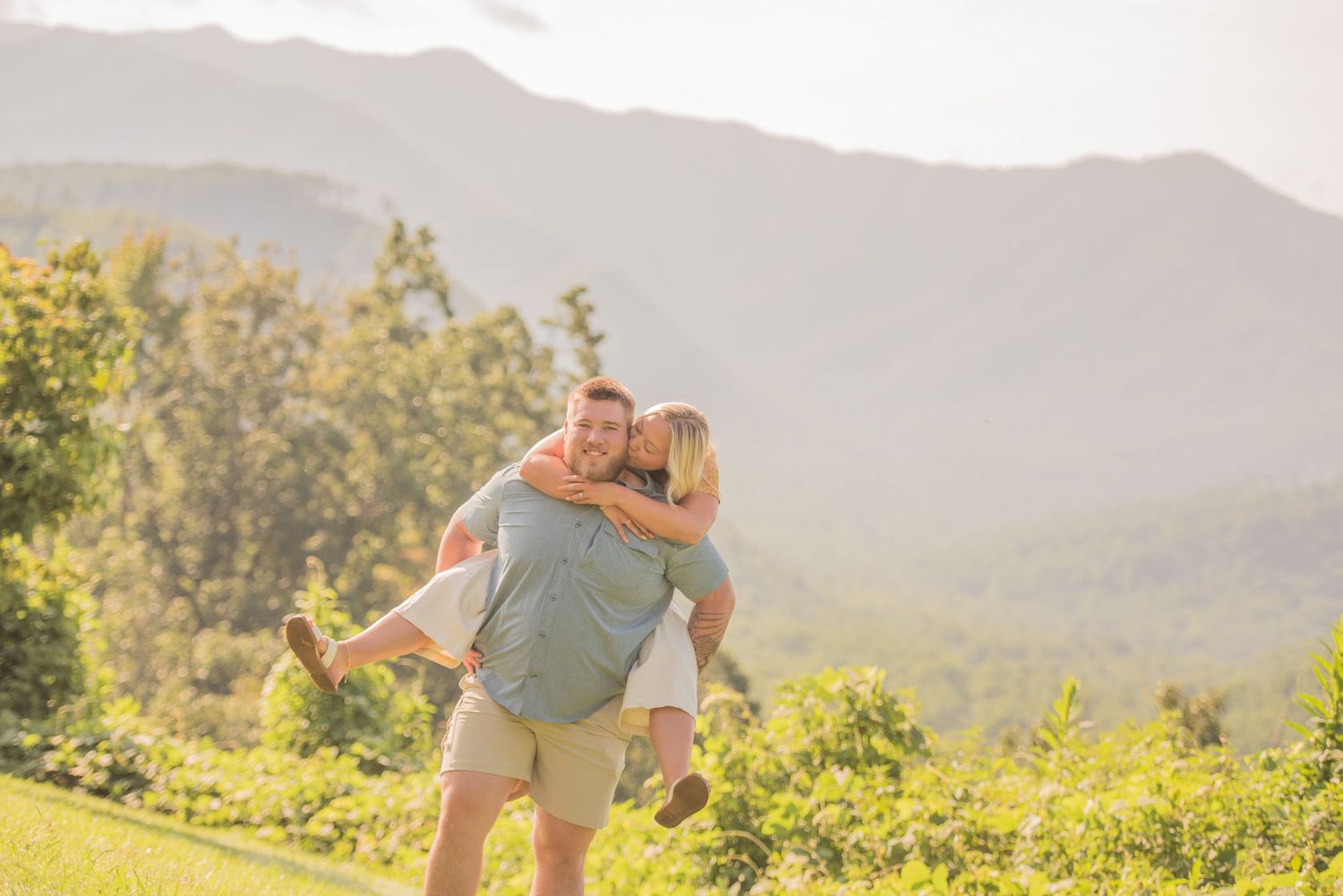 An anniversary  joyful couple embraces against a beautiful mountain backdrop during golden hour in a scenic outdoor setting.