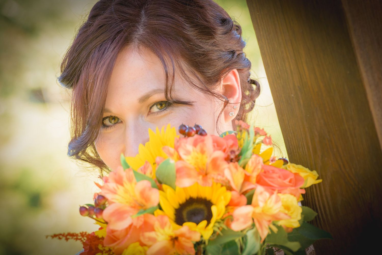 Someone holds a vibrant autumn bouquet with sunflowers and coral blooms in soft golden light in Pigeon Forge.