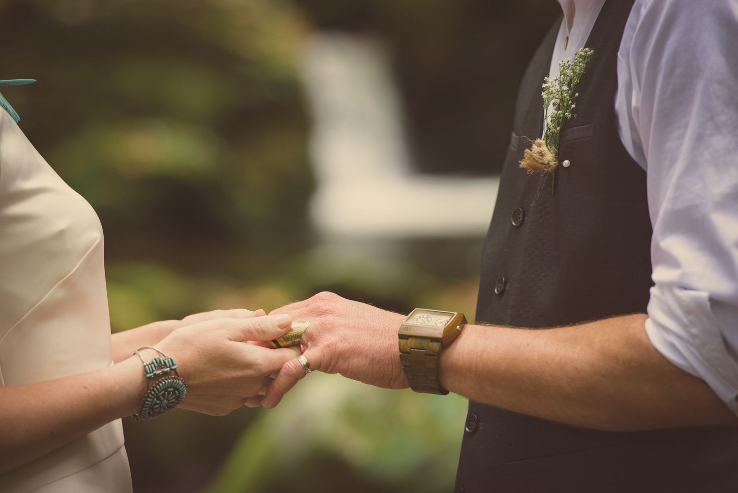 Two people holding hands during an outdoor wedding ceremony with one wearing a vest and white shirt by Gatlinburg Wedding Photographers.