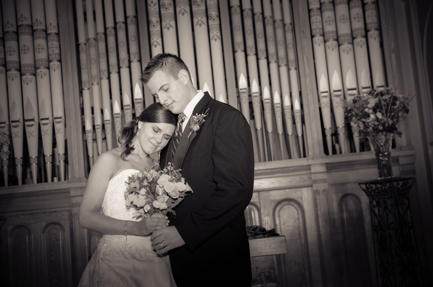 A romantic black and white wedding portrait with the couple embracing in front of an ornate church organ Wears Valley TN.
