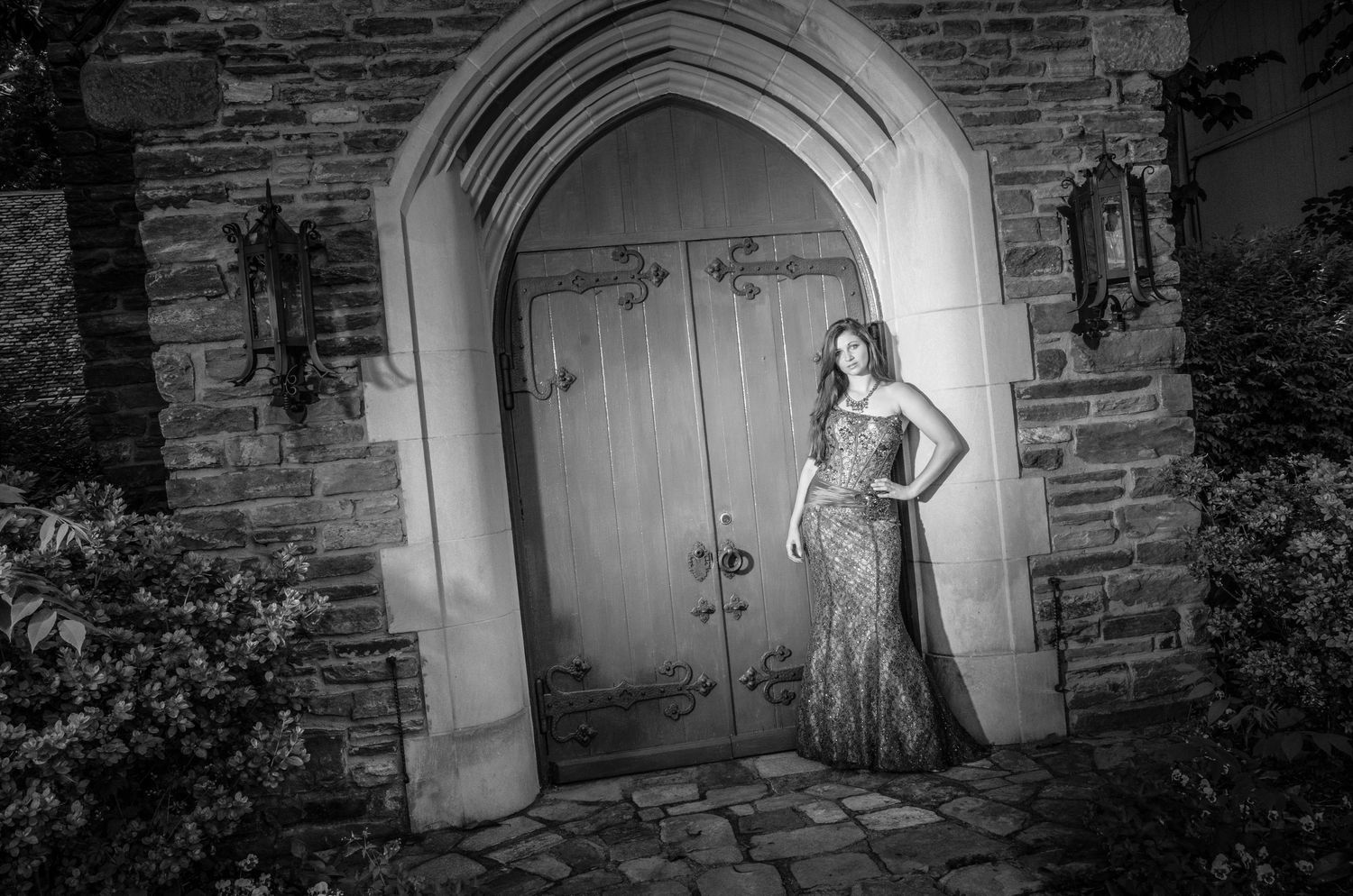 A vintage-style black and white photograph taken in front of a gothic stone church doorway with arched architecture.