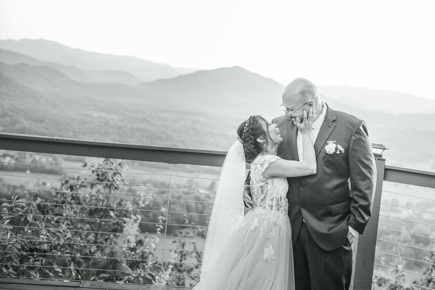 A tender moment captured in black and white photography at a scenic mountain wedding venue with vast landscape views.