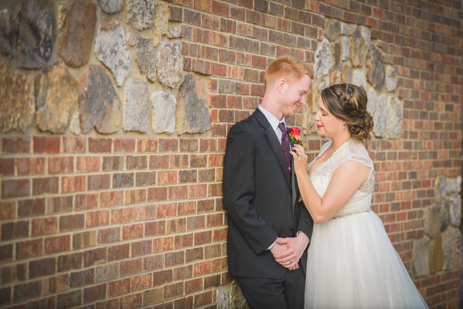 A couple shares a tender moment against a rustic brick wall during their wedding ceremony by Pigeon Forge Wedding Photographers.