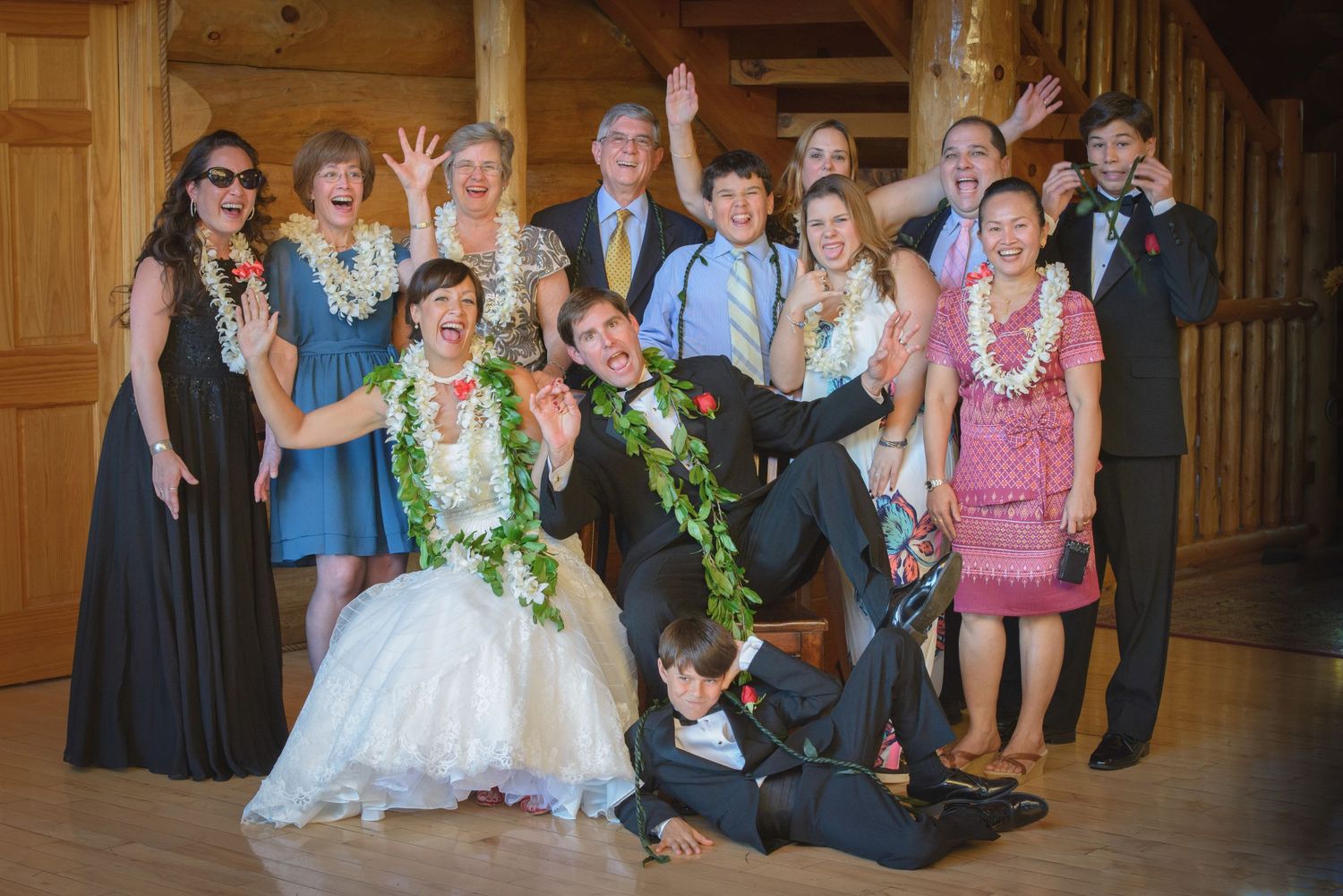 Wedding party group poses together in Hawaii-themed attire with leis and formal wear at rustic indoor venue in Pigeon Forge.