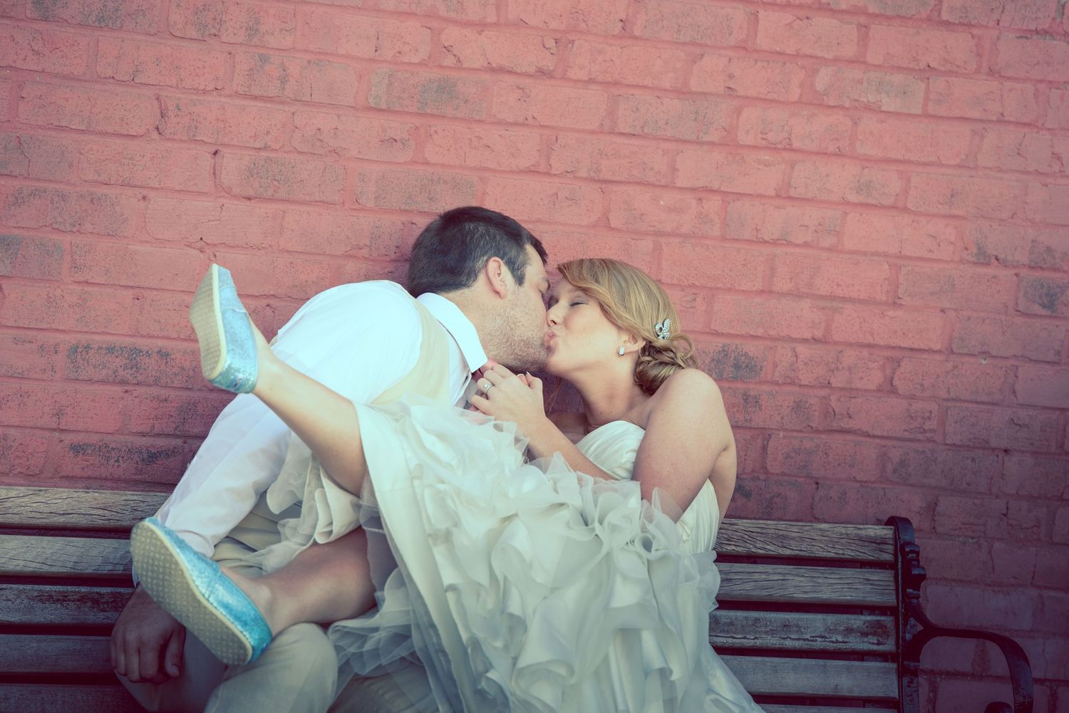 Romantic couple in wedding attire share an intimate moment against a red brick wall in Sevierville TN