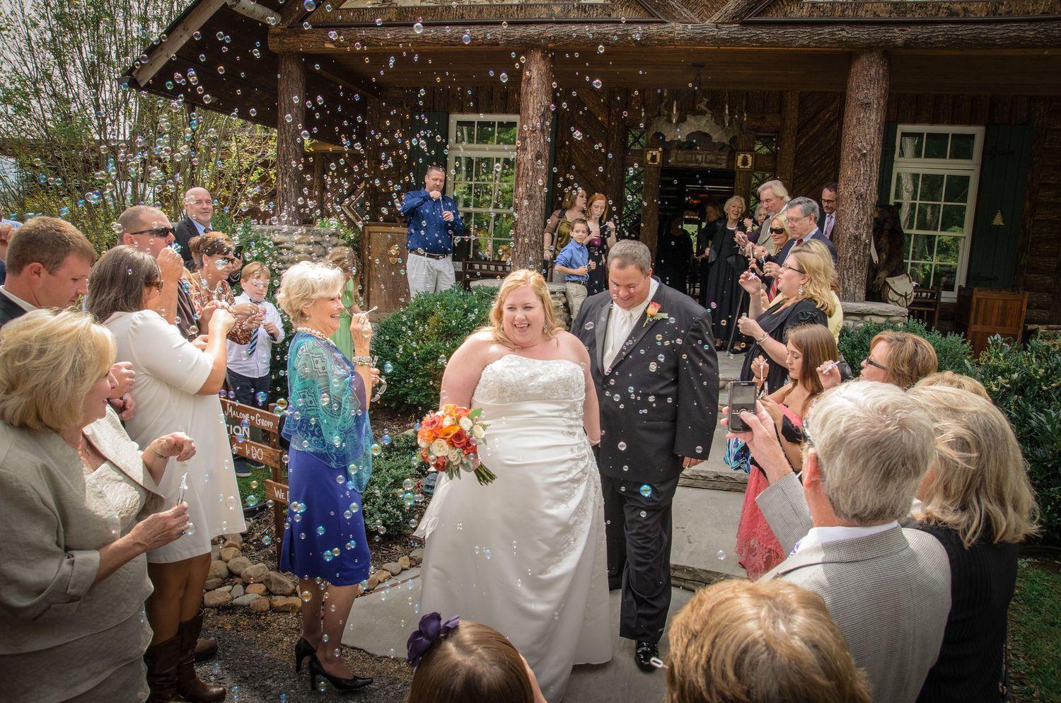 Guests throw confetti over newlyweds exiting rustic venue during summer wedding celebration in Knoxville TN.