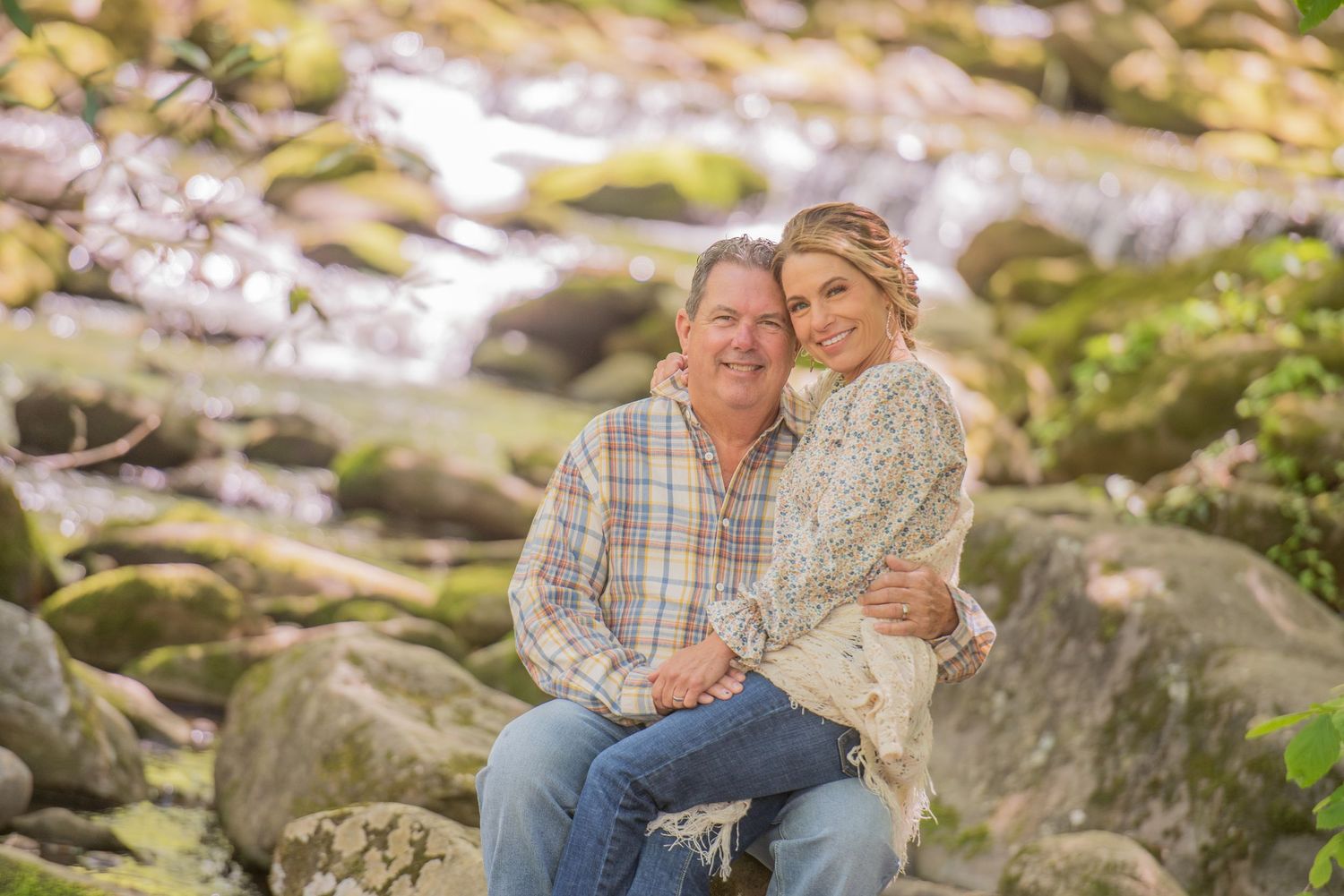 Gatlinburg tn anniversary photographers portrait of an older couple with creek in background surrounded by mountain waterfall.
