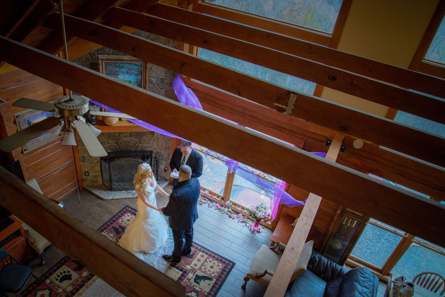 A couple stands together in an empty wooden church with sunlight streaming through stained glass windows by Gatlinburg Wedding Photographers