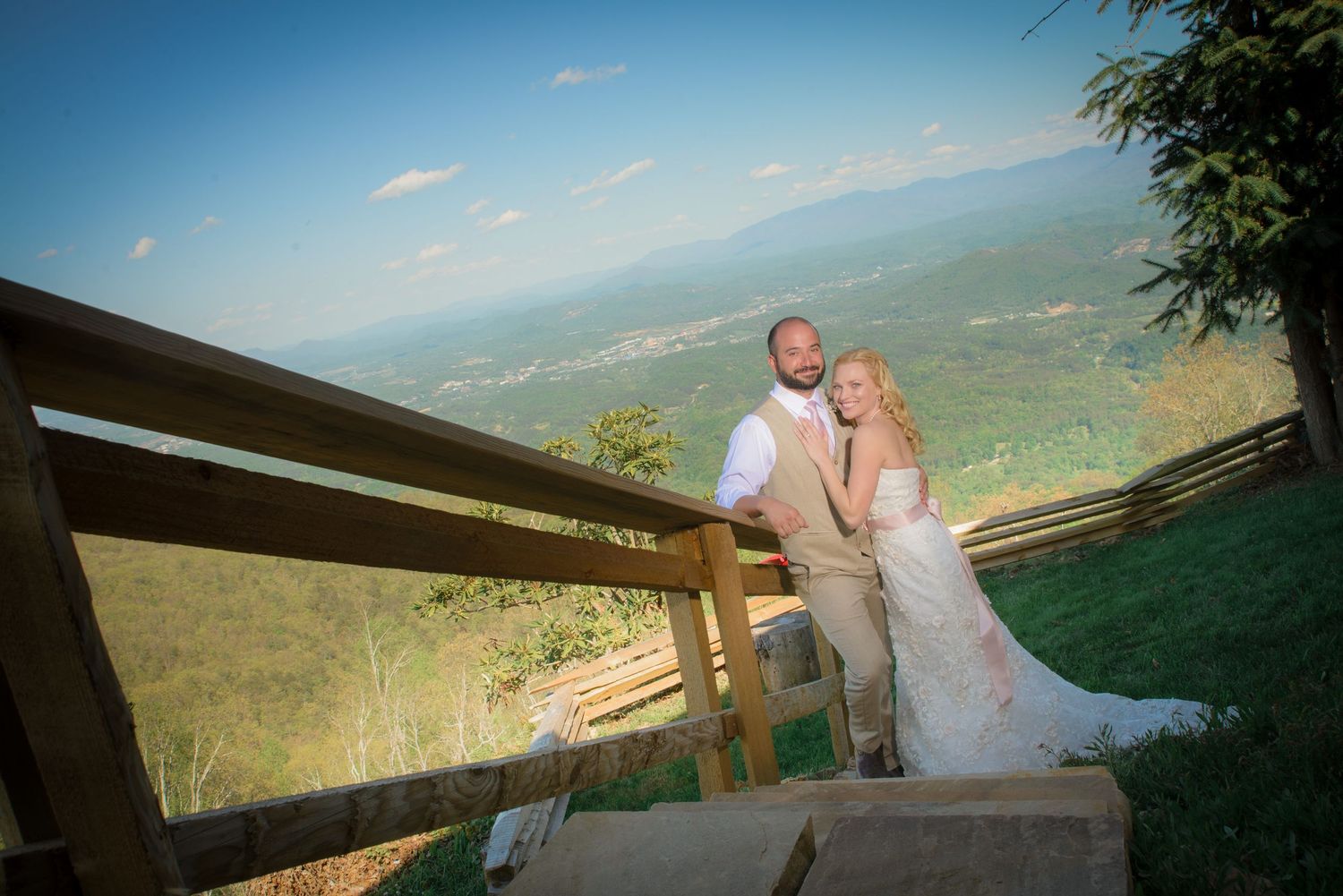 Sevierville wedding Photographer portrait of couple in wedding attire embrace on a scenic mountain overlook deck with sweeping valley views.