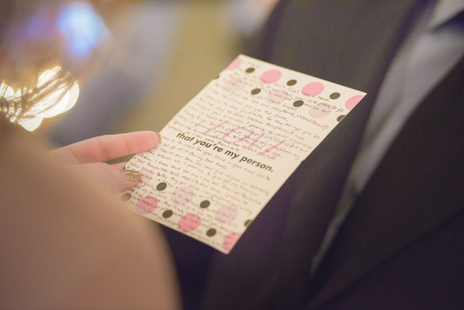 A delicate floral wedding program or invitation card being held in soft lighting conditions by Gatlinburg Wedding Photographers TN.