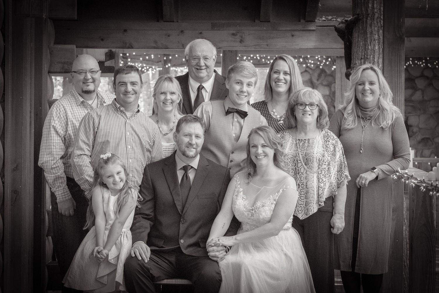A group poses together in formal attire at a rustic venue in black and white photography by Pigeon Forge Photographers.