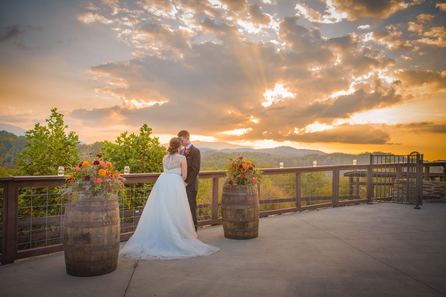Gatlinburg Wedding Photographers TN portrait of a romantic sunset on a terrace decorated with rustic wine barrels overlooking a mountain.