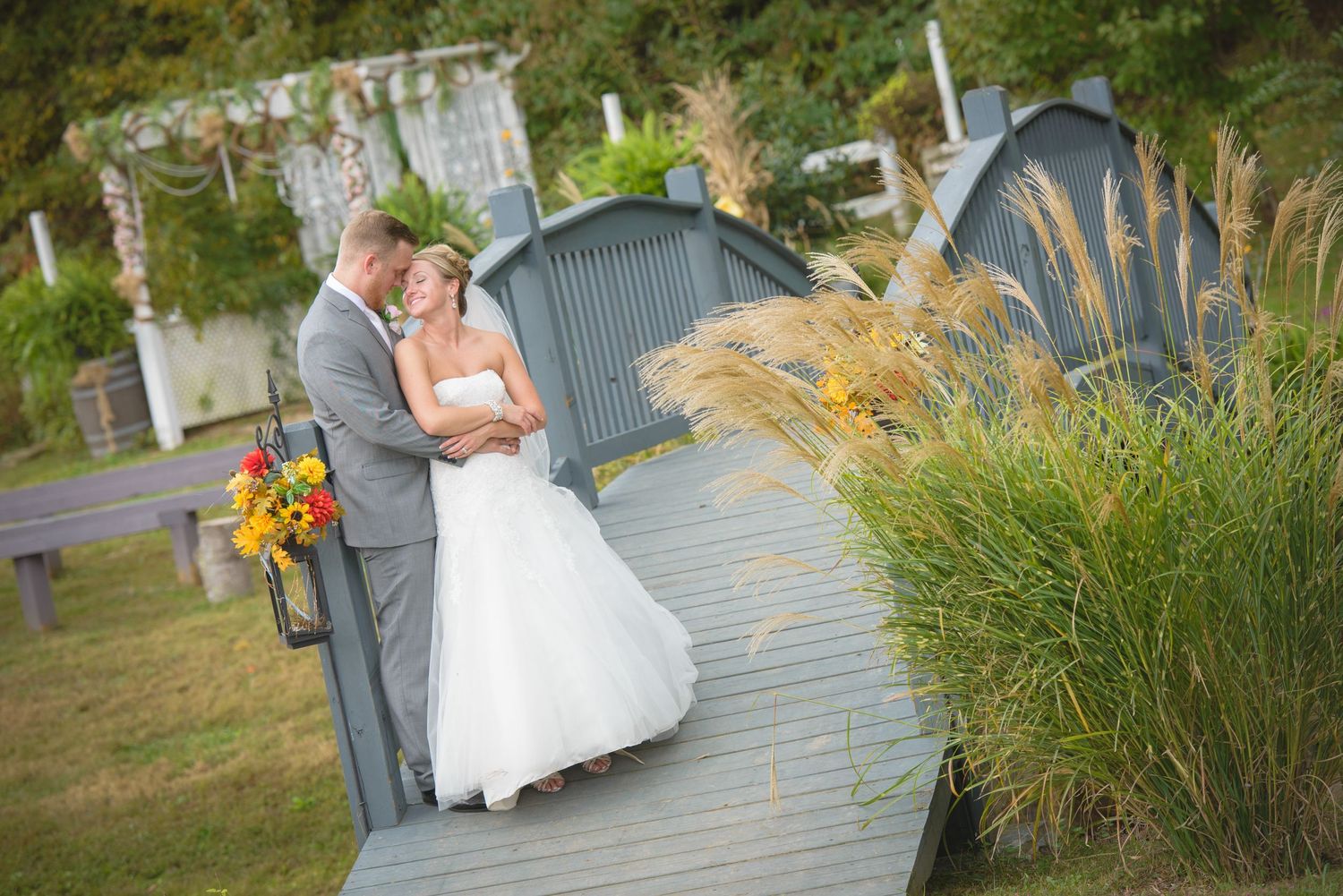 Pigeon Forge Wedding Photographers of wedding couple shares romantic moment on wooden walkway surrounded by ornamental grasses and flowers.