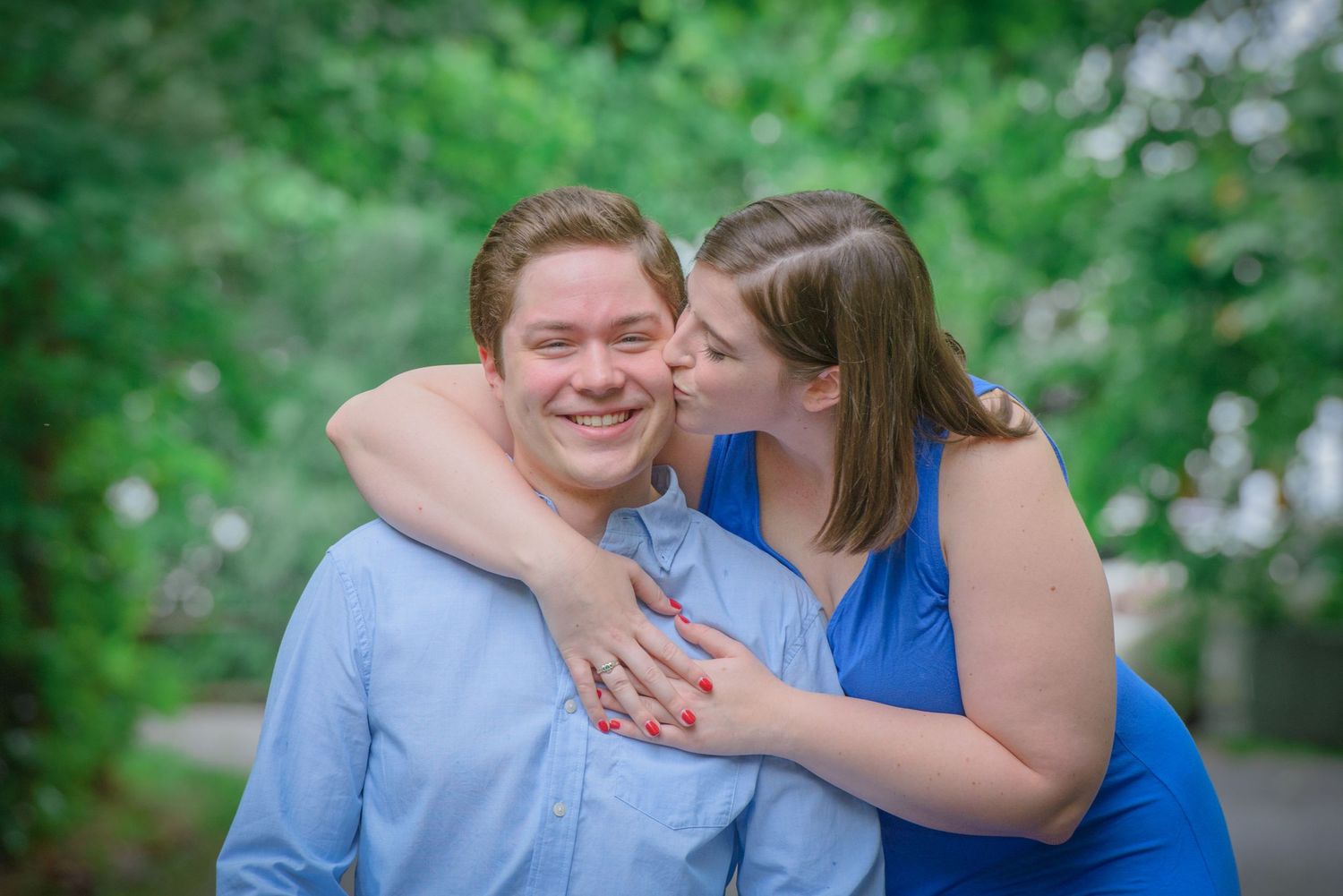 A couple embraces outdoors with bright smiles while sharing a tender moment in a lush green garden setting by Sevierville TN Photographers.