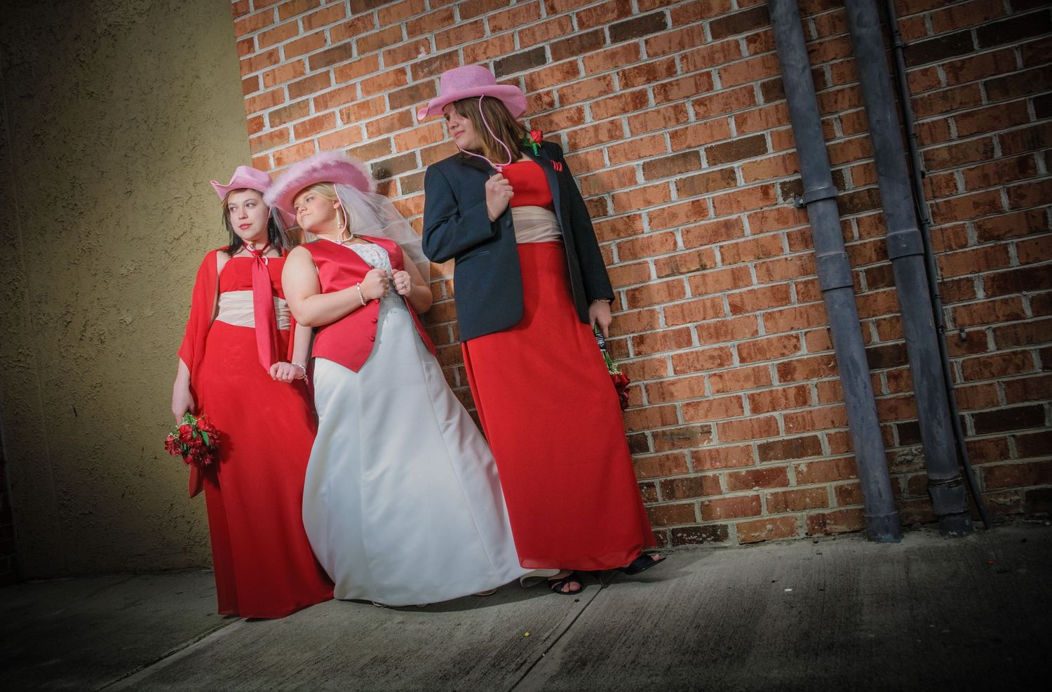Bride and bridesmaid in red and white formal attire pose against a brick wall during what appears to be a wedding in Sevierville TN.