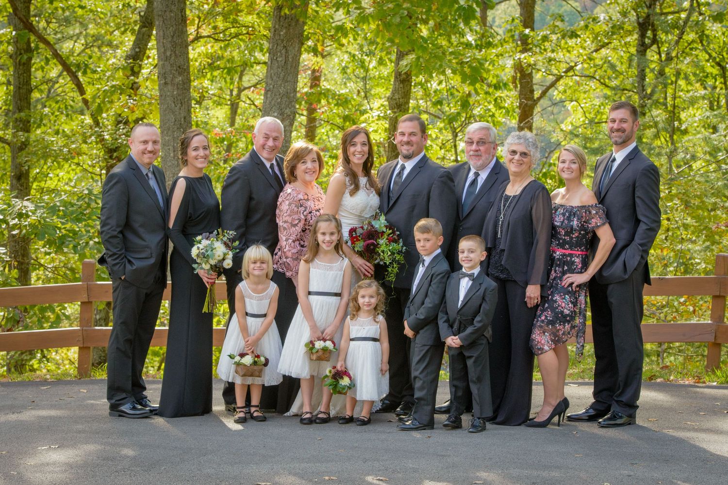 A formal group portrait taken in summer on an outdoor deck surrounded by lush green trees and foliage by Pigeon Forge Wedding Photographers.