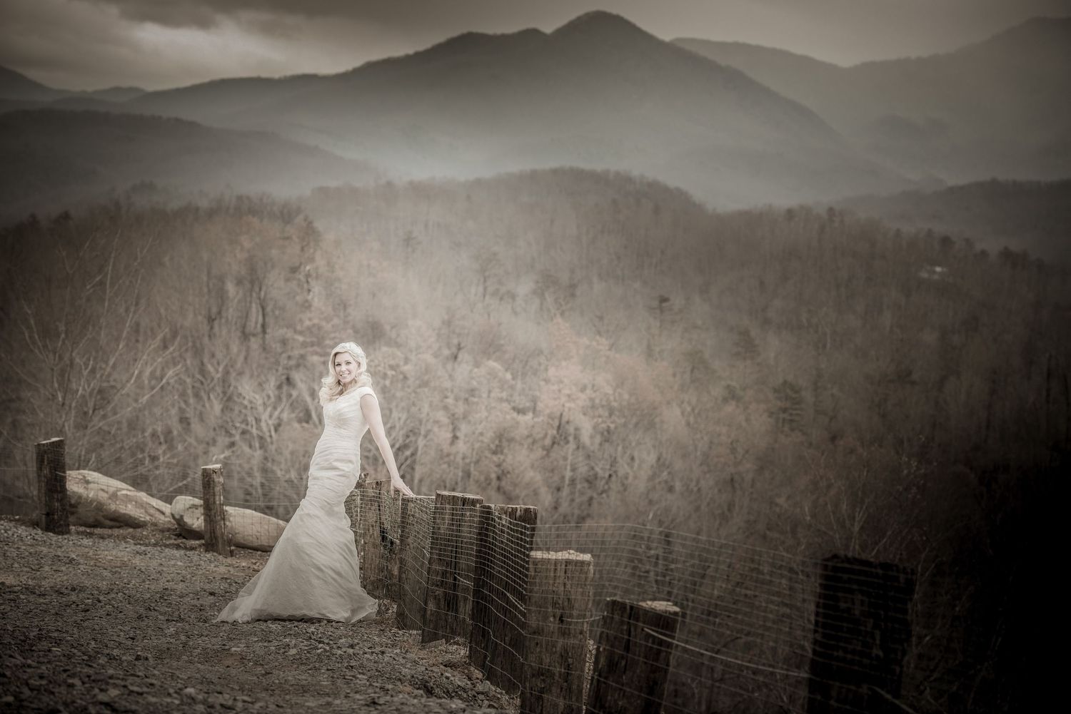 A monochrome photo of a scenic mountain overlook with rustic wood fencing in the foreground at sunset by Cosby Wedding Photographers.