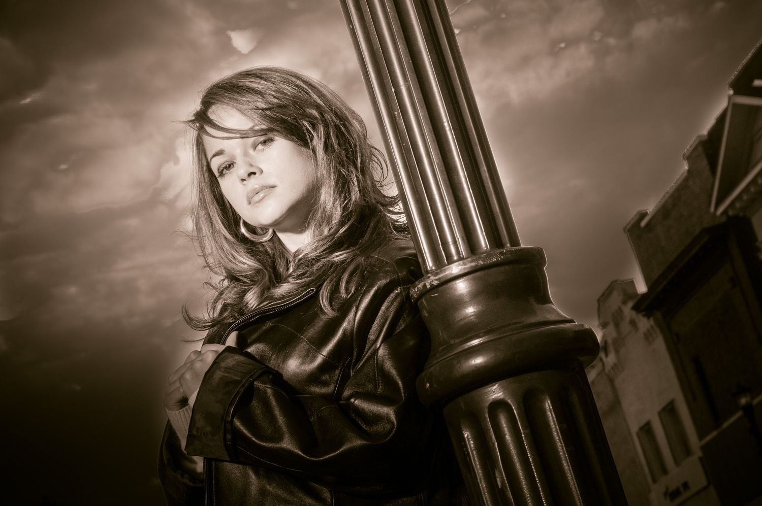 A person in medieval or fantasy costume stands beside a pillar in dramatic sepia-toned lighting.