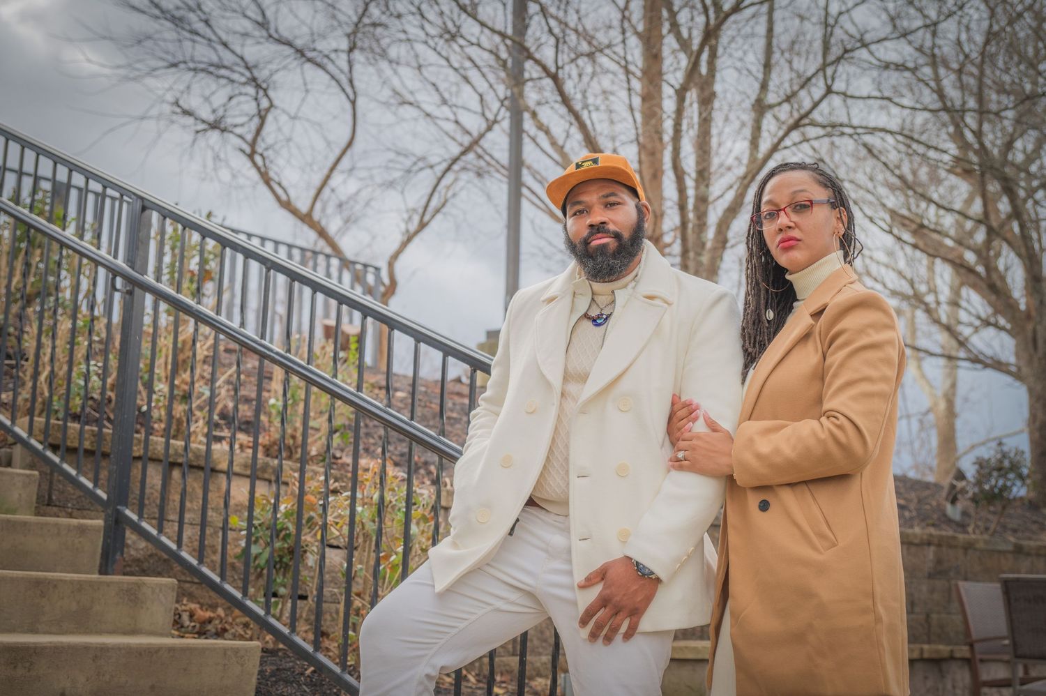 Two stylishly dressed people in coordinating beige and white outfits pose together on outdoor stone steps with metal railing in Townsend TN.