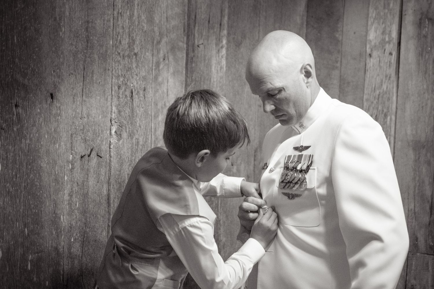 A tender black and white moment between a child and a military officer in dress whites examining medals on the uniform in Sevierville TN.