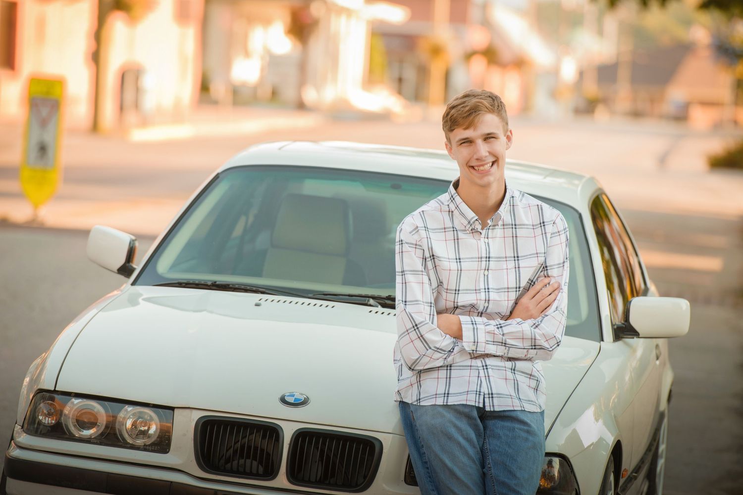 A silver BMW sedan is parked on a residential street during golden hour lighting.