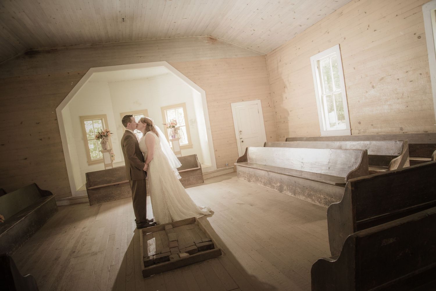 A wedding couple shares an intimate moment in a rustic church interior with wooden floors and white walls. in Cades Cove TN.