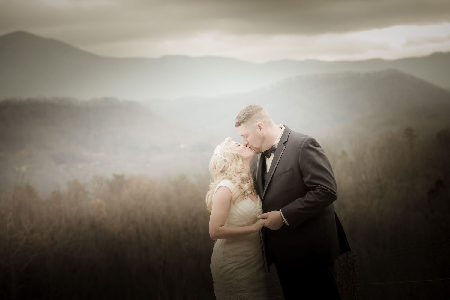 A couple shares an intimate moment against a backdrop of misty mountains during golden hour by Gatlinburg Wedding Photographers TN.