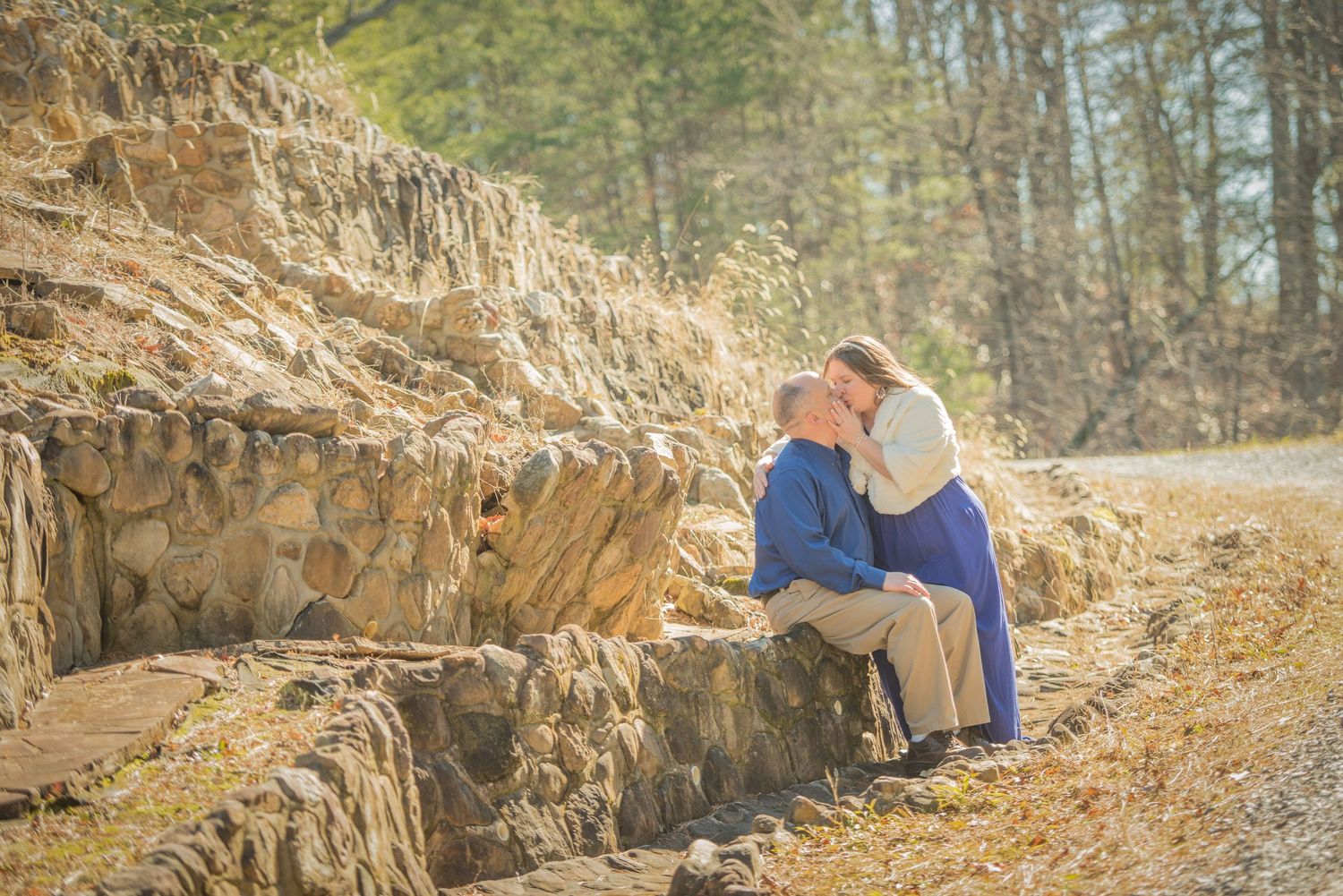 Two people in blue clothing sit close together on stone steps along a dirt path during golden hour by Sevierville TN Photographers.