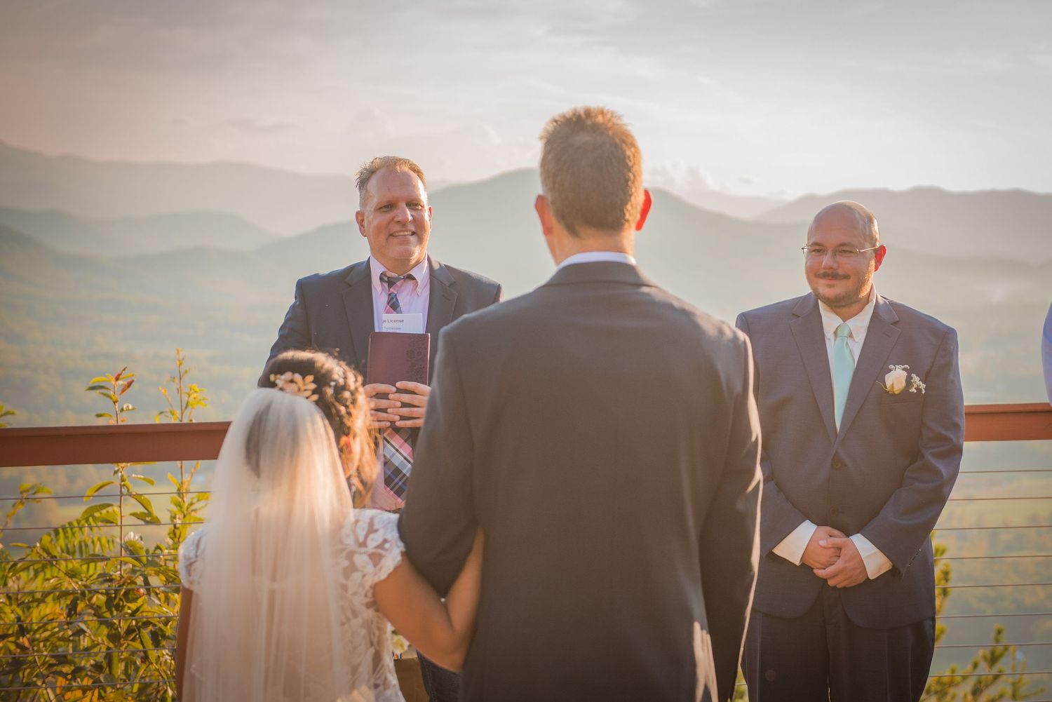 Wedding ceremony taking place on a mountaintop terrace with rolling hills and mountains in the background at sunset in Pigeon Forge TN.