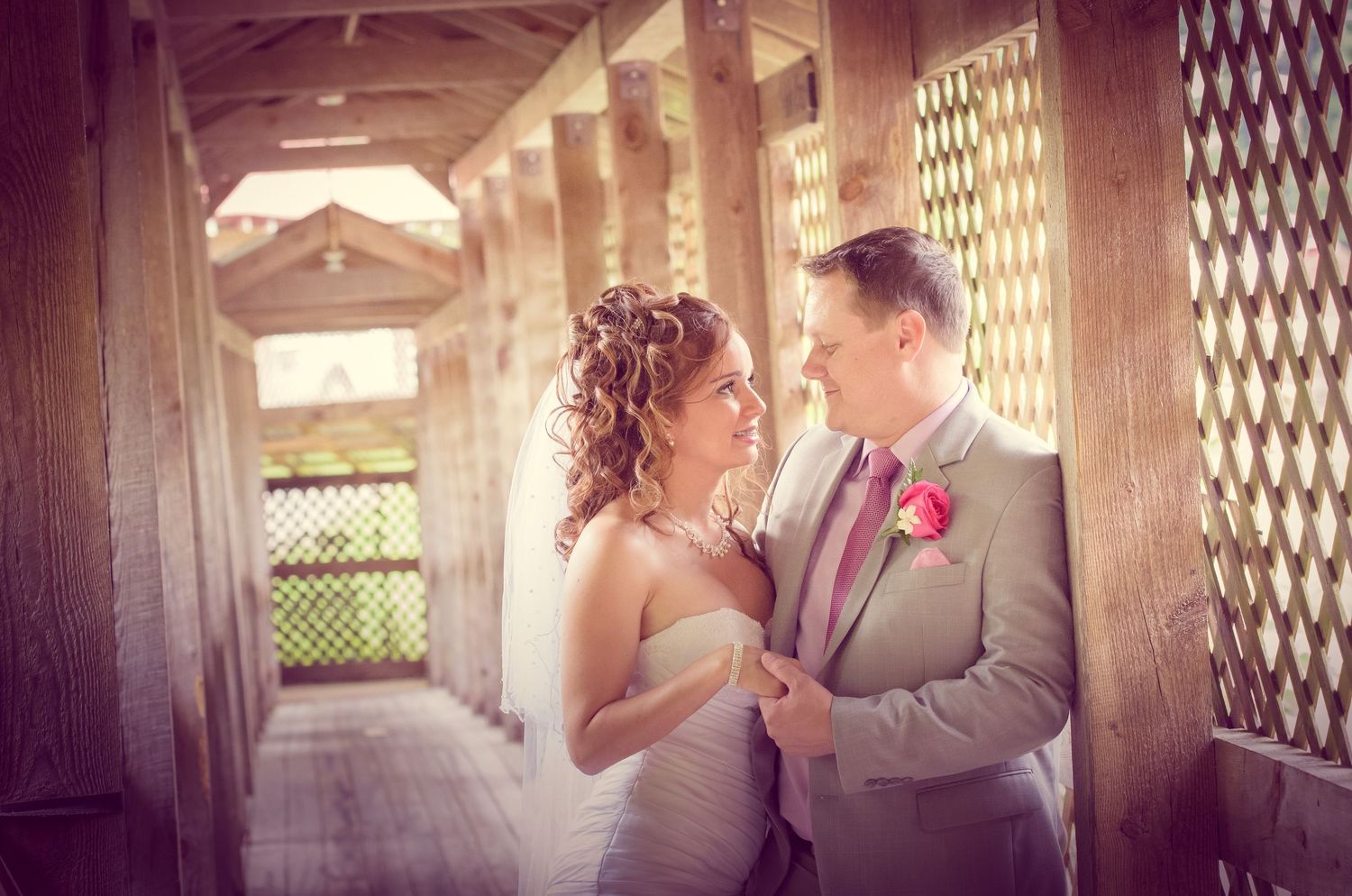 A romantic wedding moment between a couple captured in beautiful warm lighting on a rustic covered bridge walkway in Townsend TN.