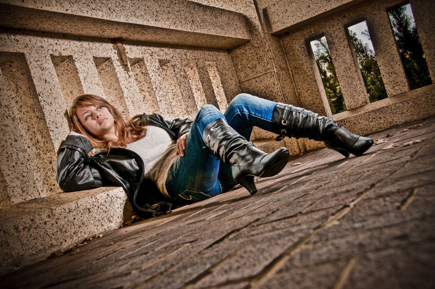 A cosplay figure in medieval fantasy attire reclines on wooden floorboards under stone archways.