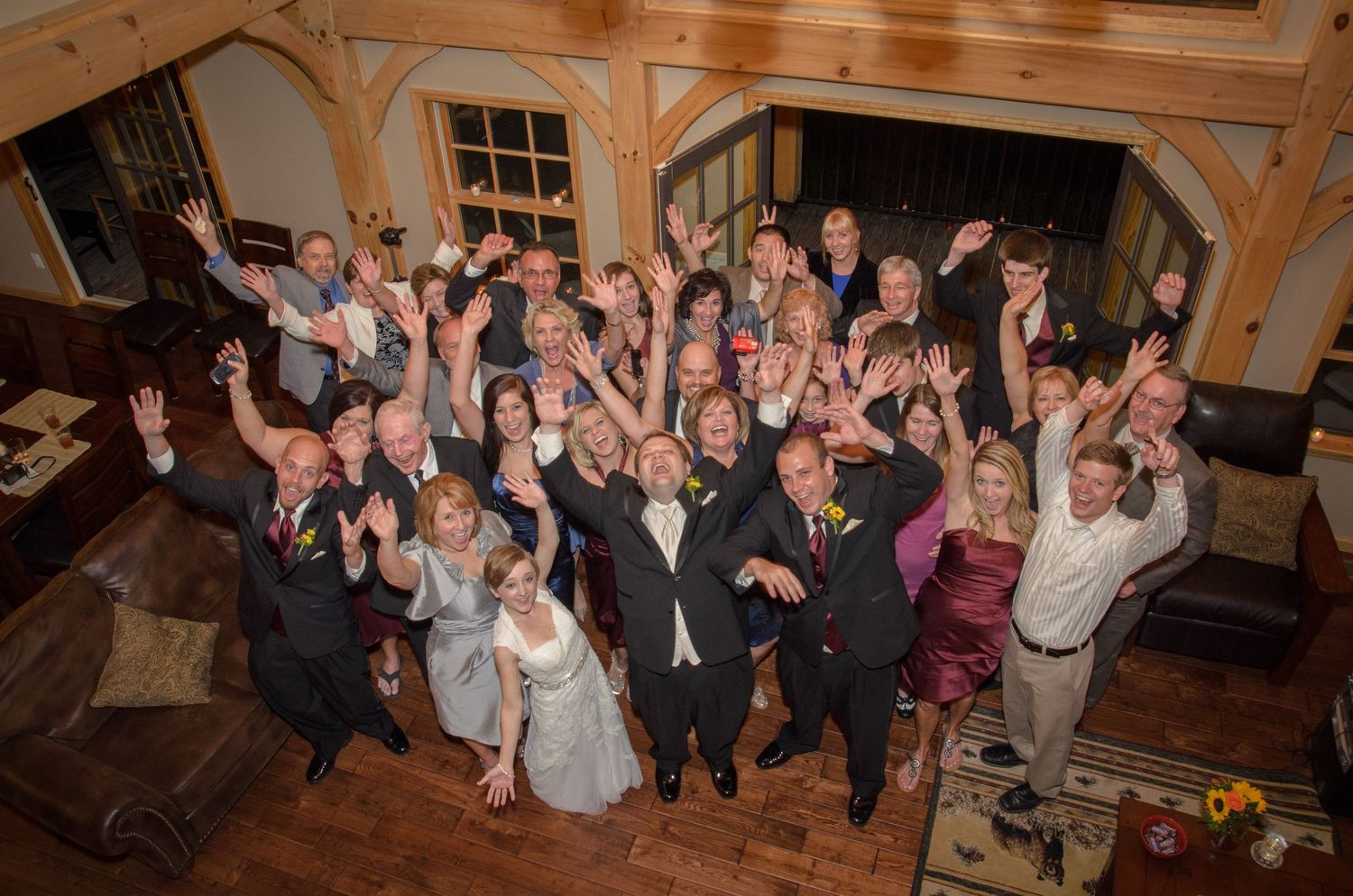 Large group of wedding guests cheering and raising their arms in celebration at a rustic wooden venue in Morristown TN.