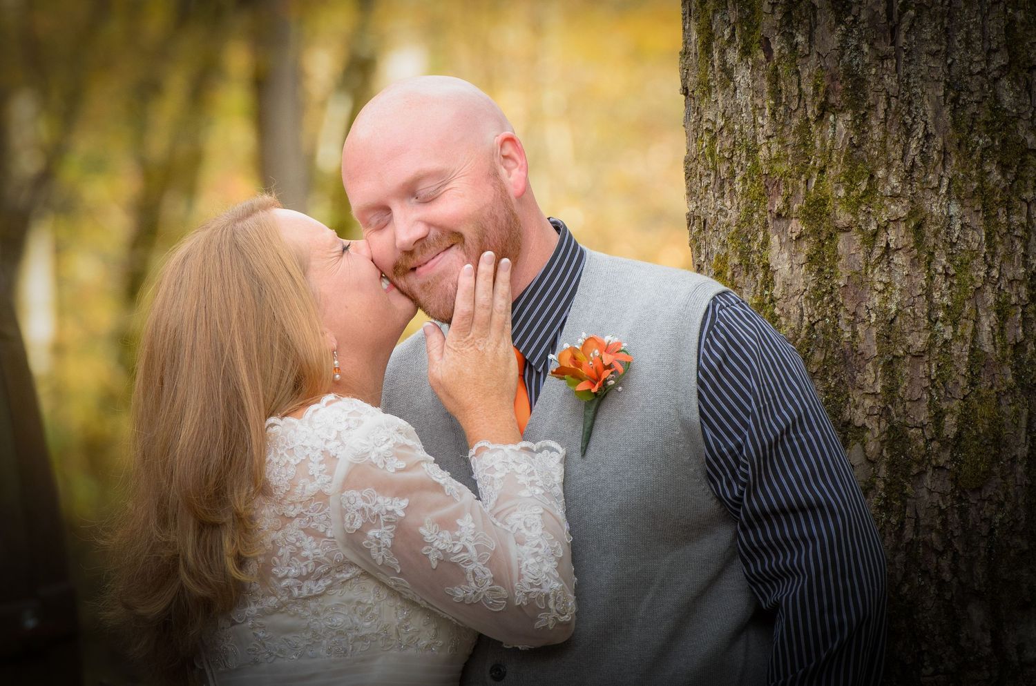 A romantic autumn wedding photo captured against a tree with soft golden bokeh in the background in Knoxville TN.