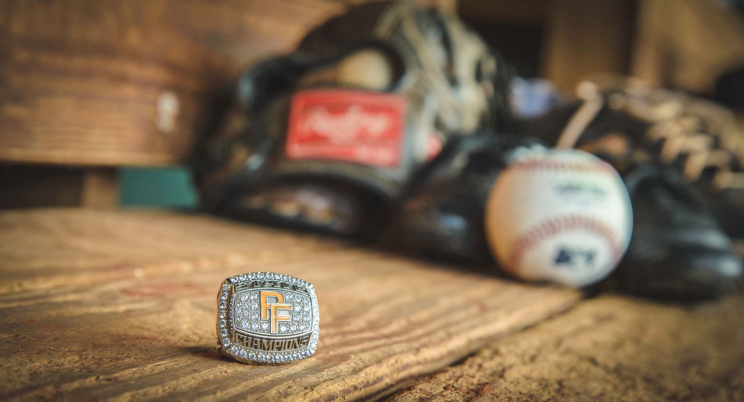 Baseball championship ring displayed with baseball glove and ball in soft focus background.