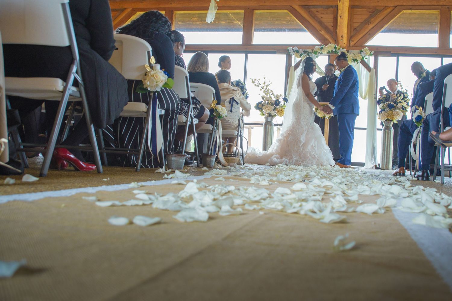 Indoor wedding ceremony with flower petals scattered on the floor as couple stands at altar surrounded by seated guests in Cosby  TN.