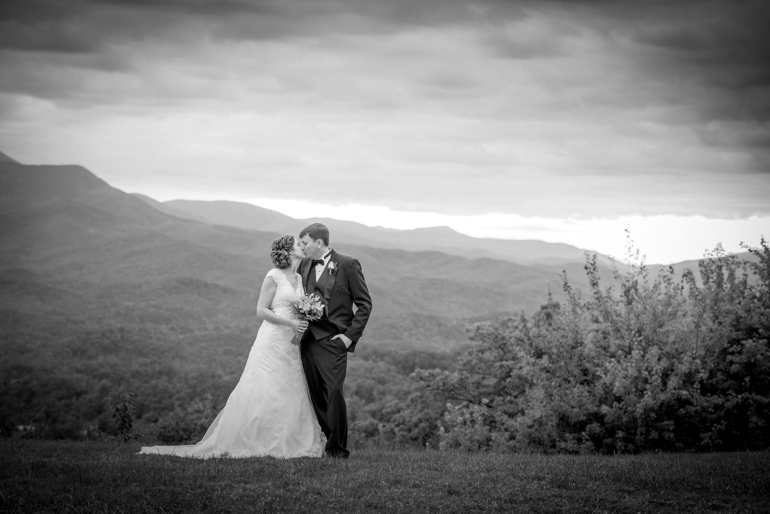 A romantic wedding couple embraces on a hilltop overlooking a misty mountain landscape by Gatlinburg TN Wedding Photographers