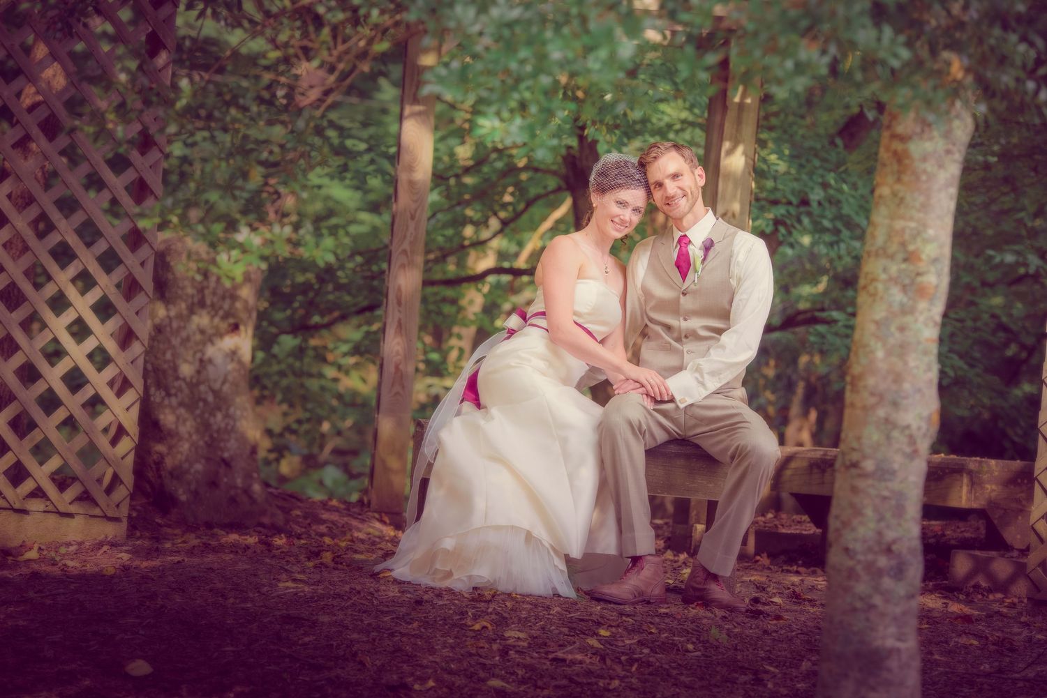 A romantic outdoor wedding portrait captured through a lattice frame as the couple sits together on a bench by Sevierville Photographers.