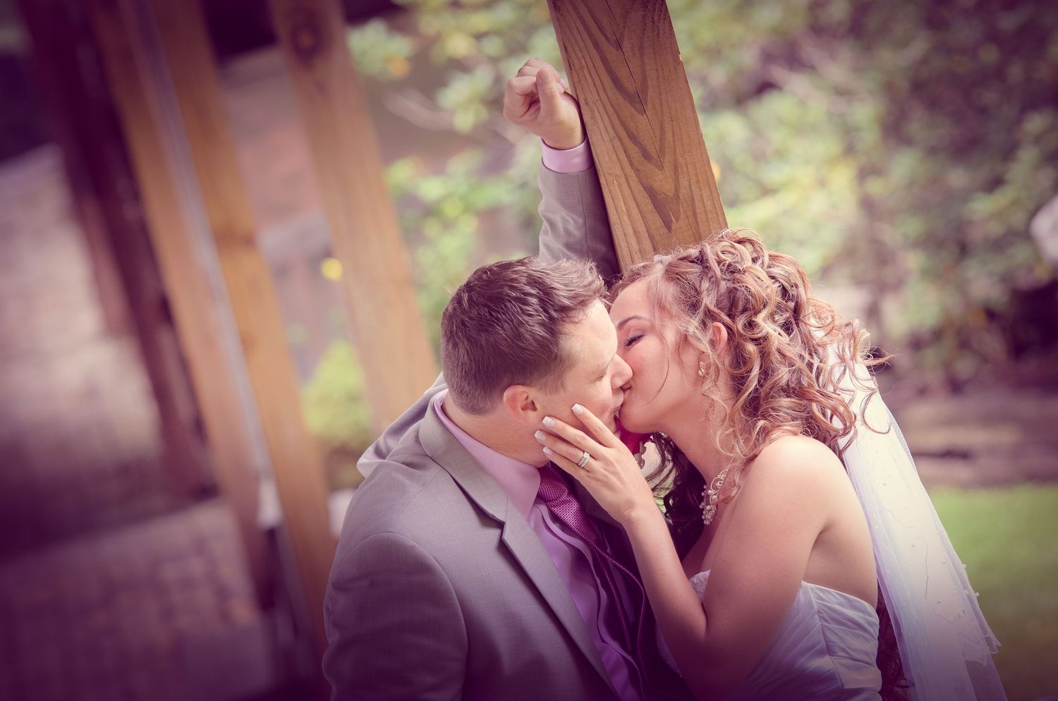 A newlywed couple shares a romantic kiss in a garden setting with soft dreamy lighting and greenery in the background in Gatlinburg TN.