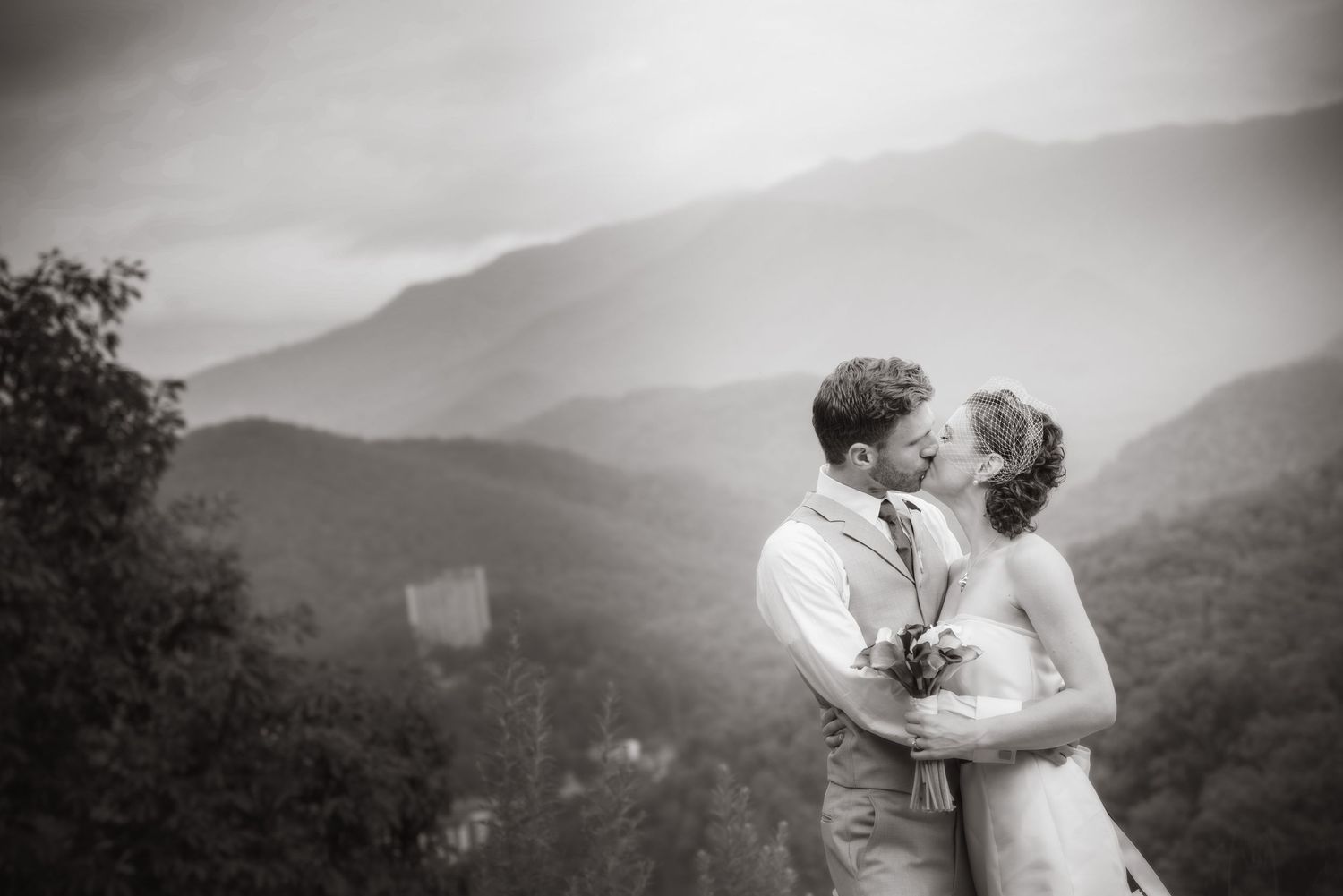 A romantic wedding couple embraces against a misty mountain backdrop by Gatlinburg TN Wedding Photographers.