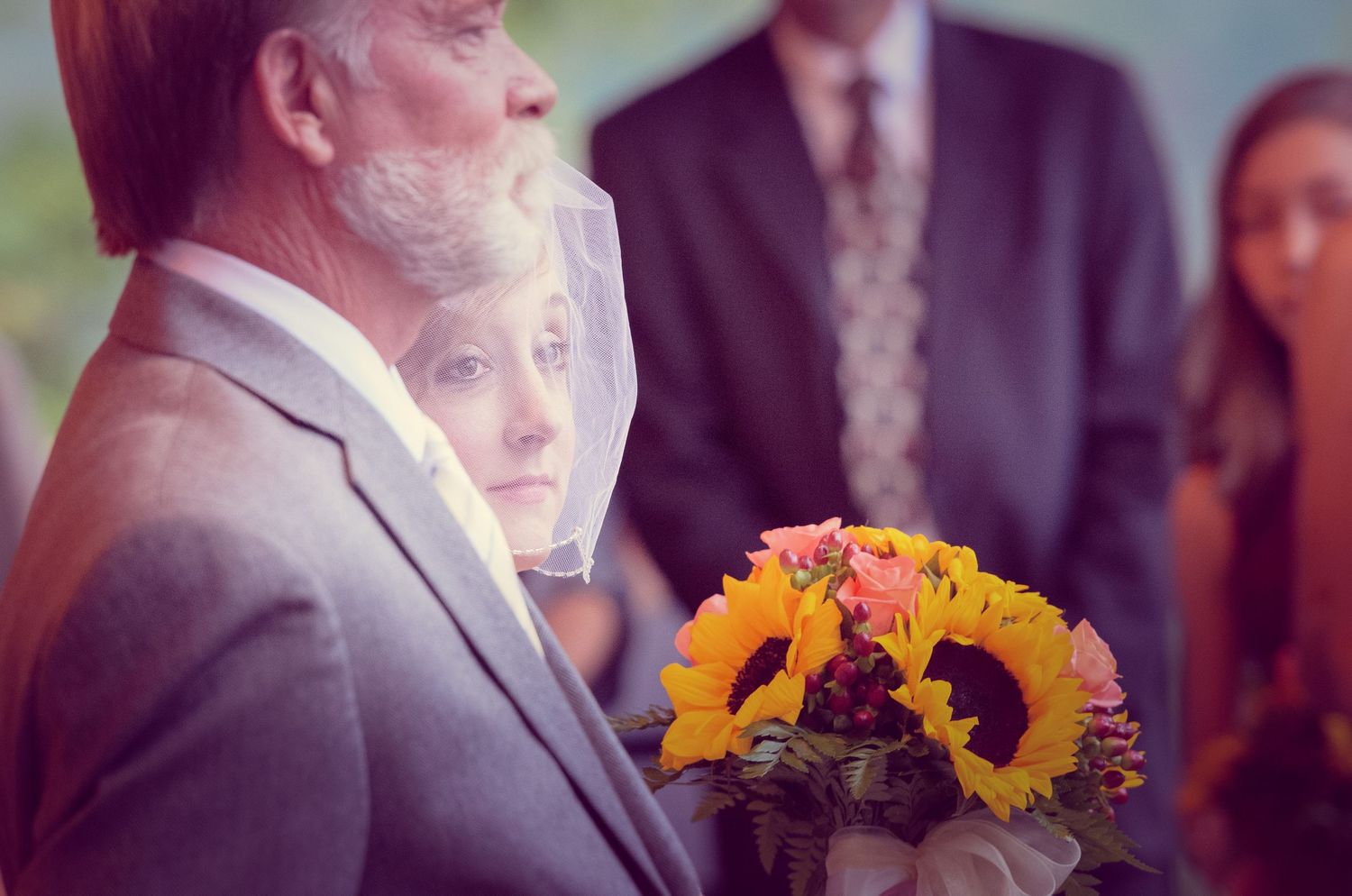 A bright sunflower and deep red rose bouquet held at an outdoor wedding ceremony in Morristown TN.