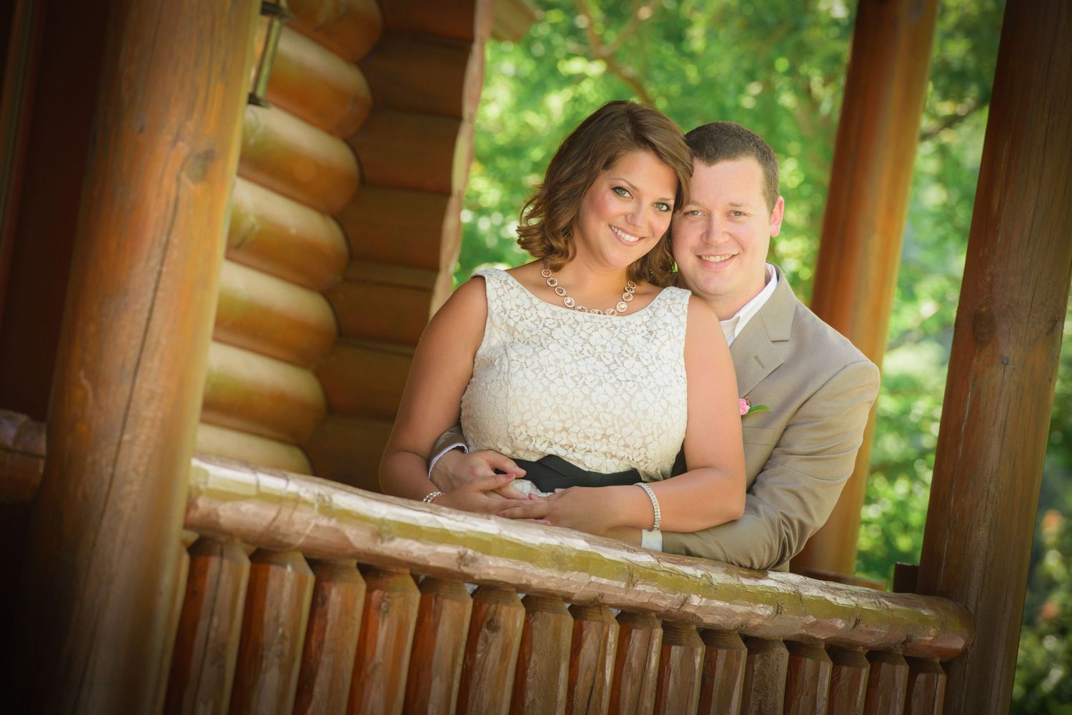 A couple poses together on a rustic log cabin porch during an engagement photoshoot in Townsend TN.